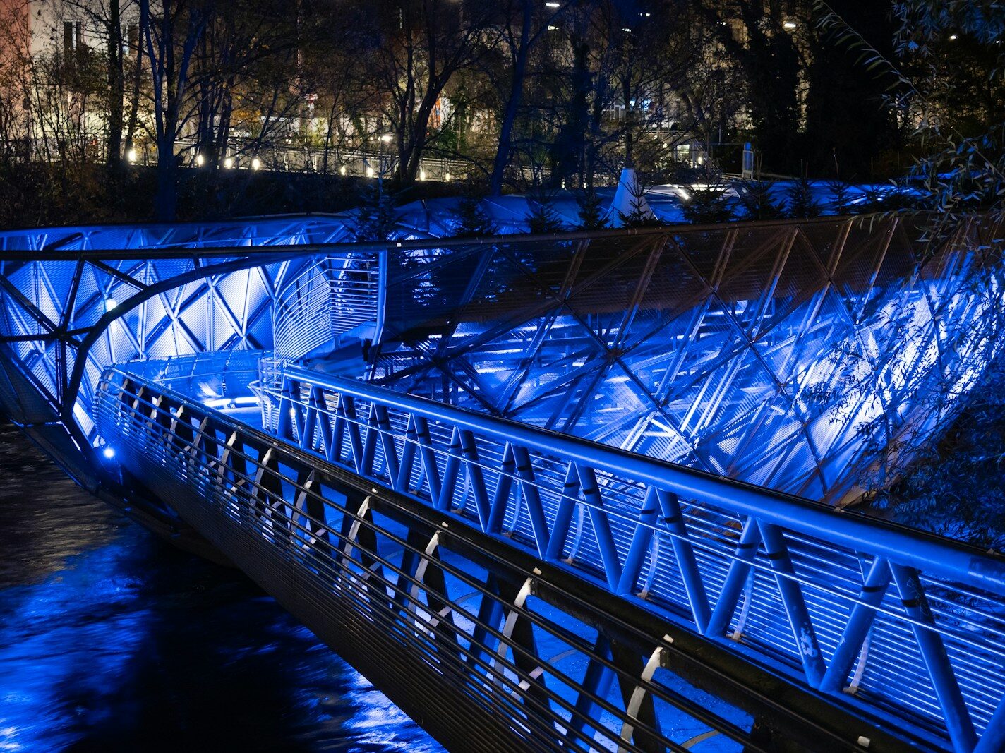a blue lit bridge over a river at night