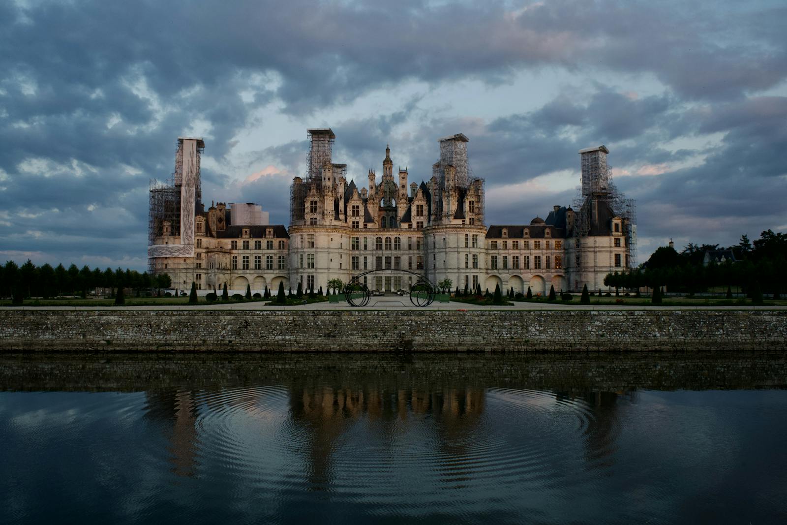 Stunning evening view of Château de Chambord reflecting in water under dramatic clouds.