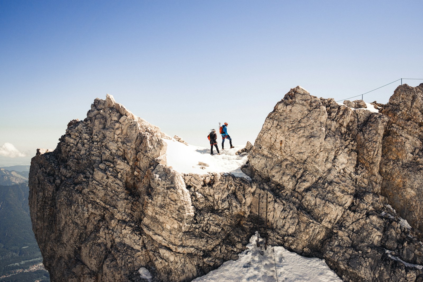 2 person sitting on snow covered mountain during daytime