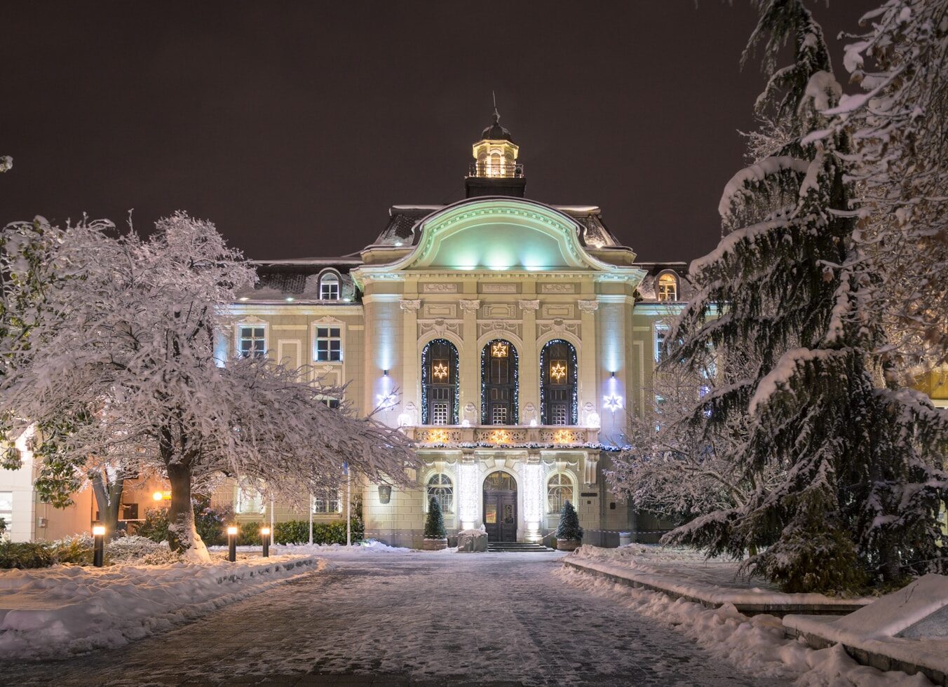 a large building surrounded by snow covered trees