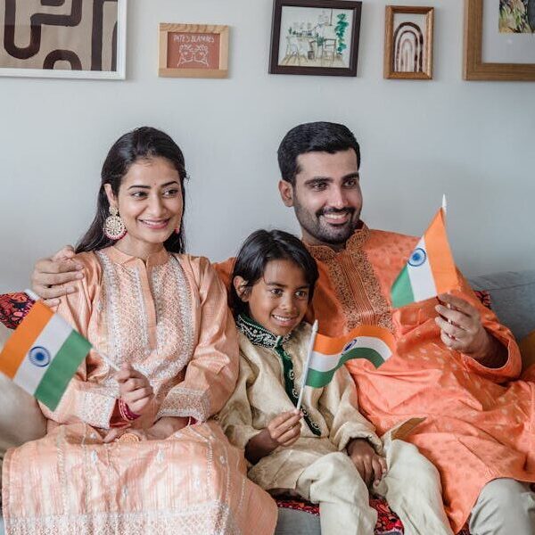 Family in traditional clothing celebrating with Indian flags on a sofa at home.