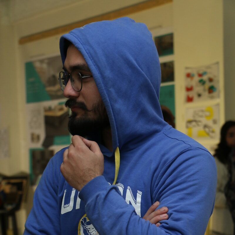 a man wearing a blue hoodie and holding a yellow stick