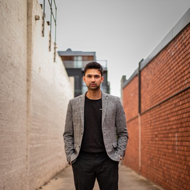 man in gray suit jacket and black pants standing on brown concrete pathway during daytime