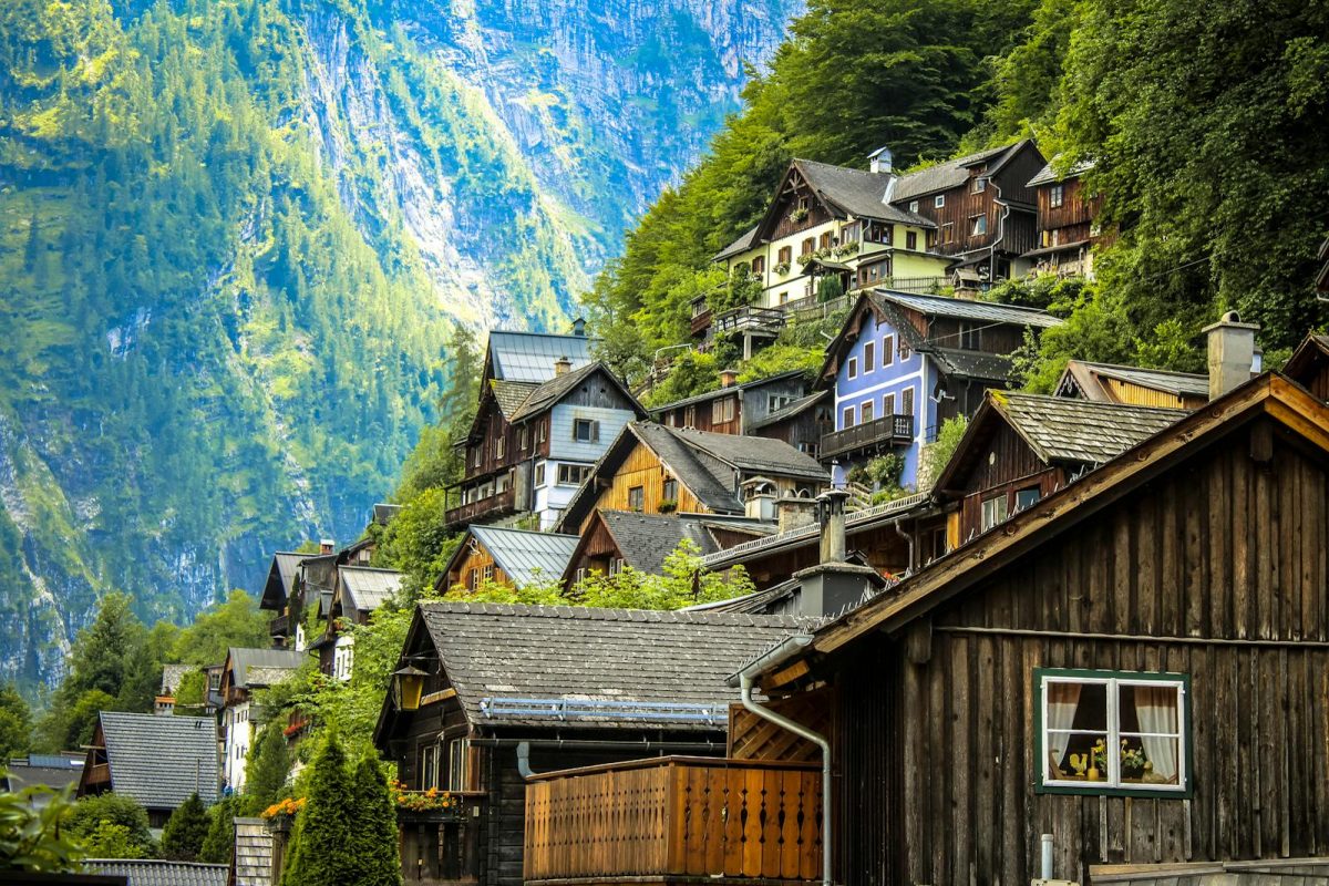 Charming wooden houses on a lush mountainside in Hallstatt, Austria under bright daylight.