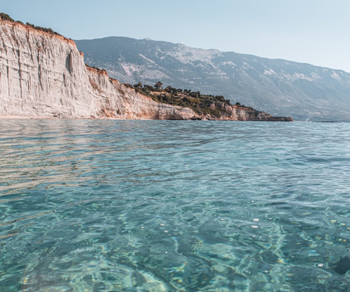 brown rocky mountain beside body of water during daytime
