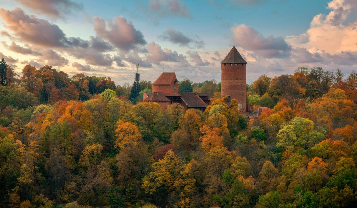 Breathtaking aerial view of Turaida Castle surrounded by vibrant autumn foliage in Sigulda, Latvia.